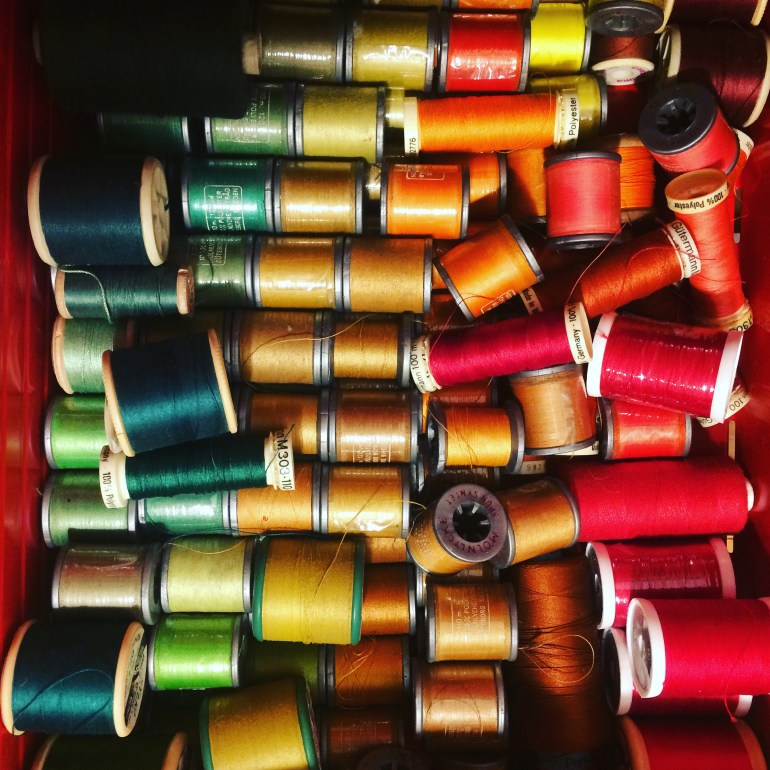 Drawer full of reels of sewing thread - green, blue, orange, yellow, red